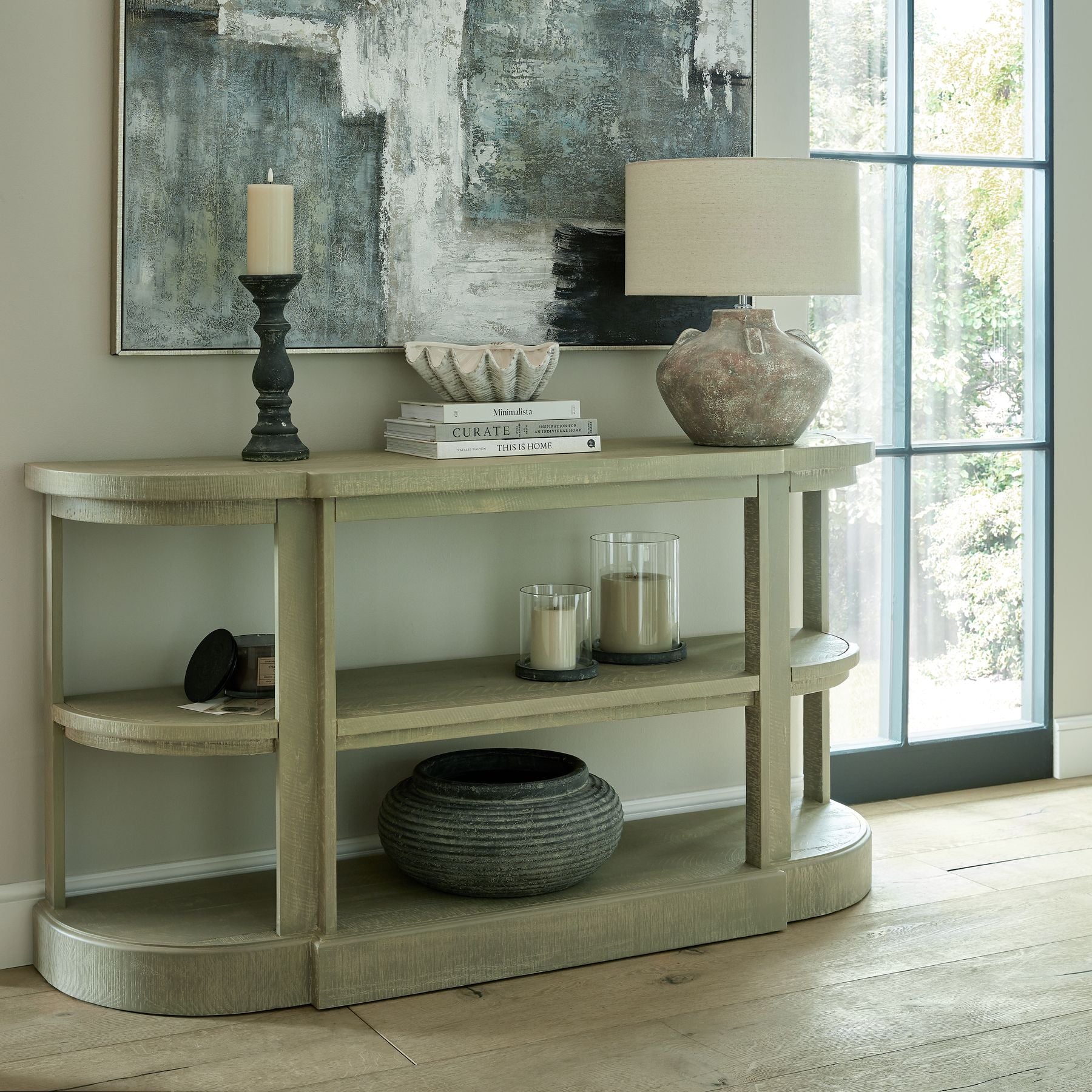 Lifestyle image of grey glass hurricane lantern on console table casting ambient glow in neutral interior
