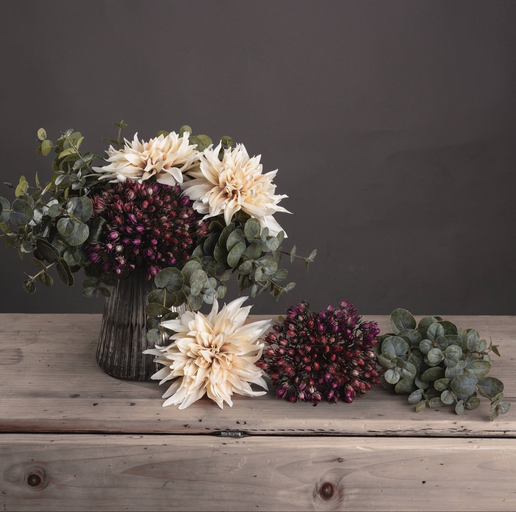 Side view of artificial eucalyptus bunch styled in vase with sculptural form