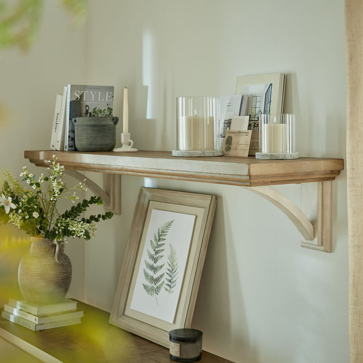 Styled interior shelf with paired Halden Hurricane Lanterns in cement and glass, shown with faux candles and framed natural art for decor inspiration