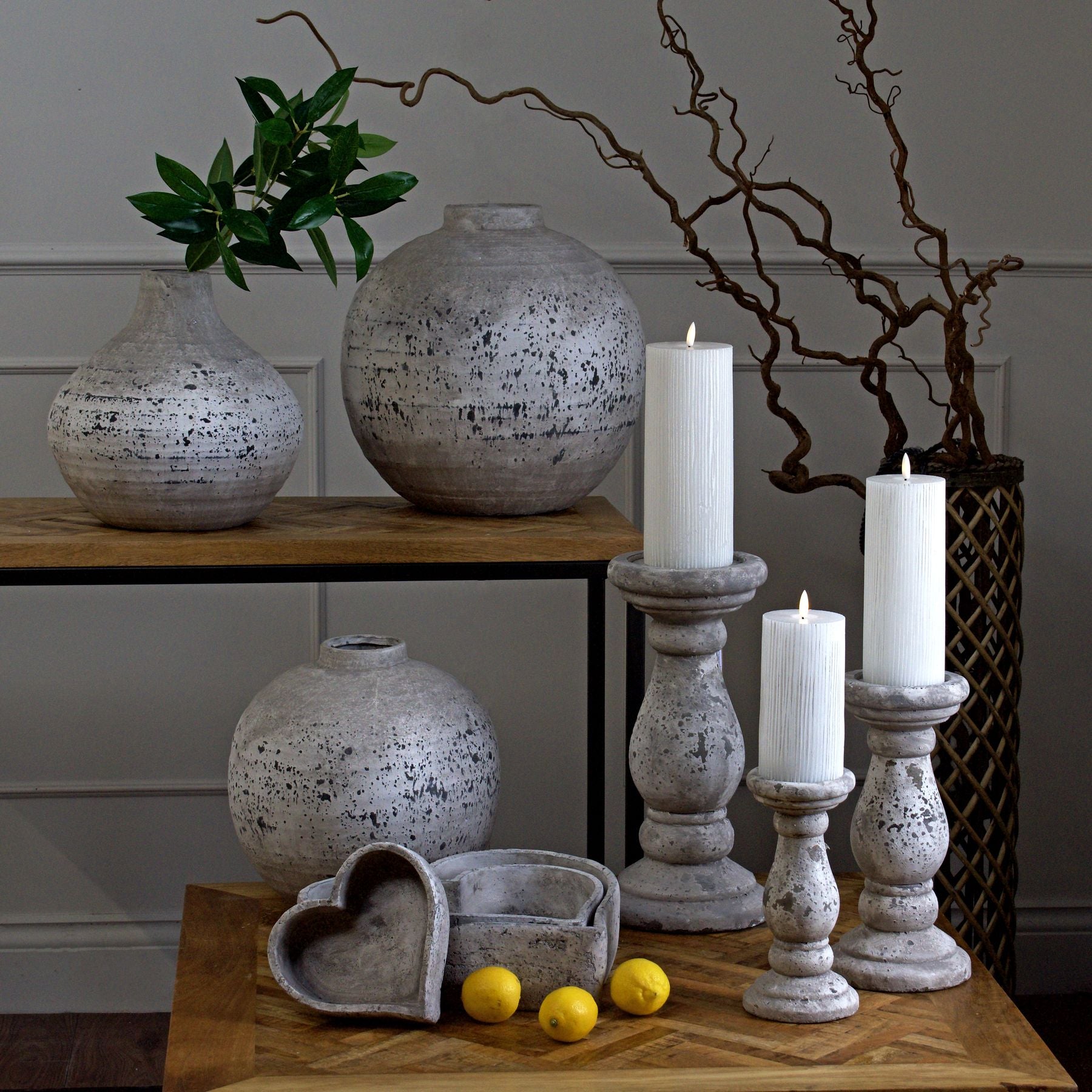 Lifestyle image of grey ceramic candle holder on wooden mantel with soft candle glow