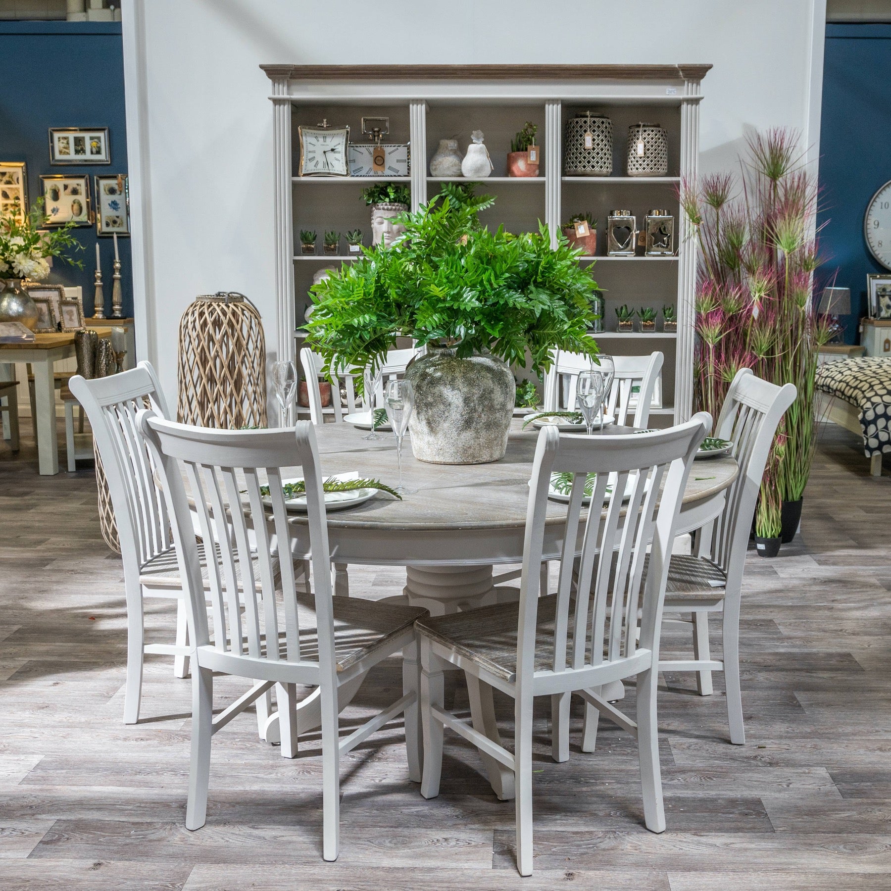Aged stone ceramic jar vase as a dining table centrepiece with green foliage.
