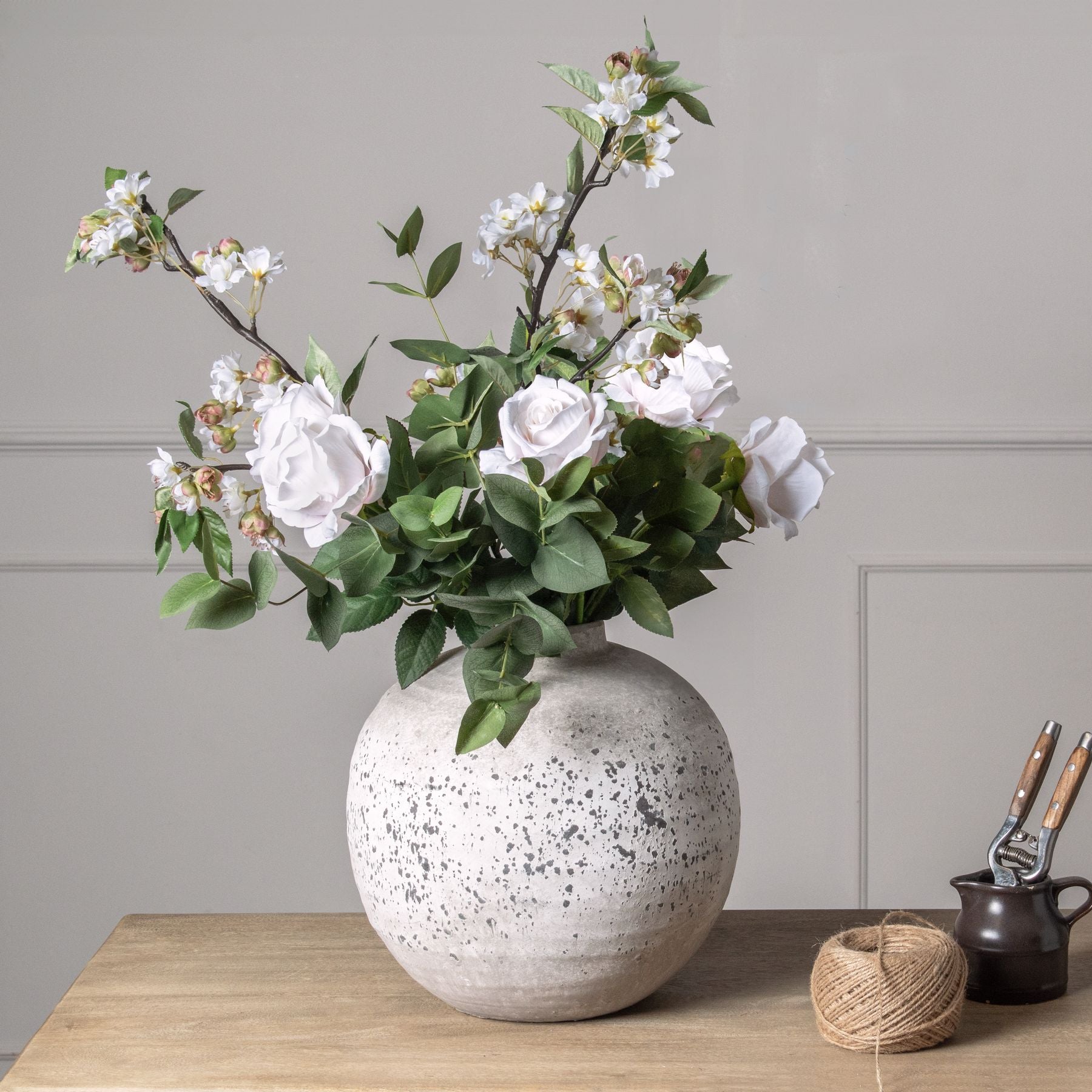 Tall faux cherry blossom stem styled in a narrow ceramic vase