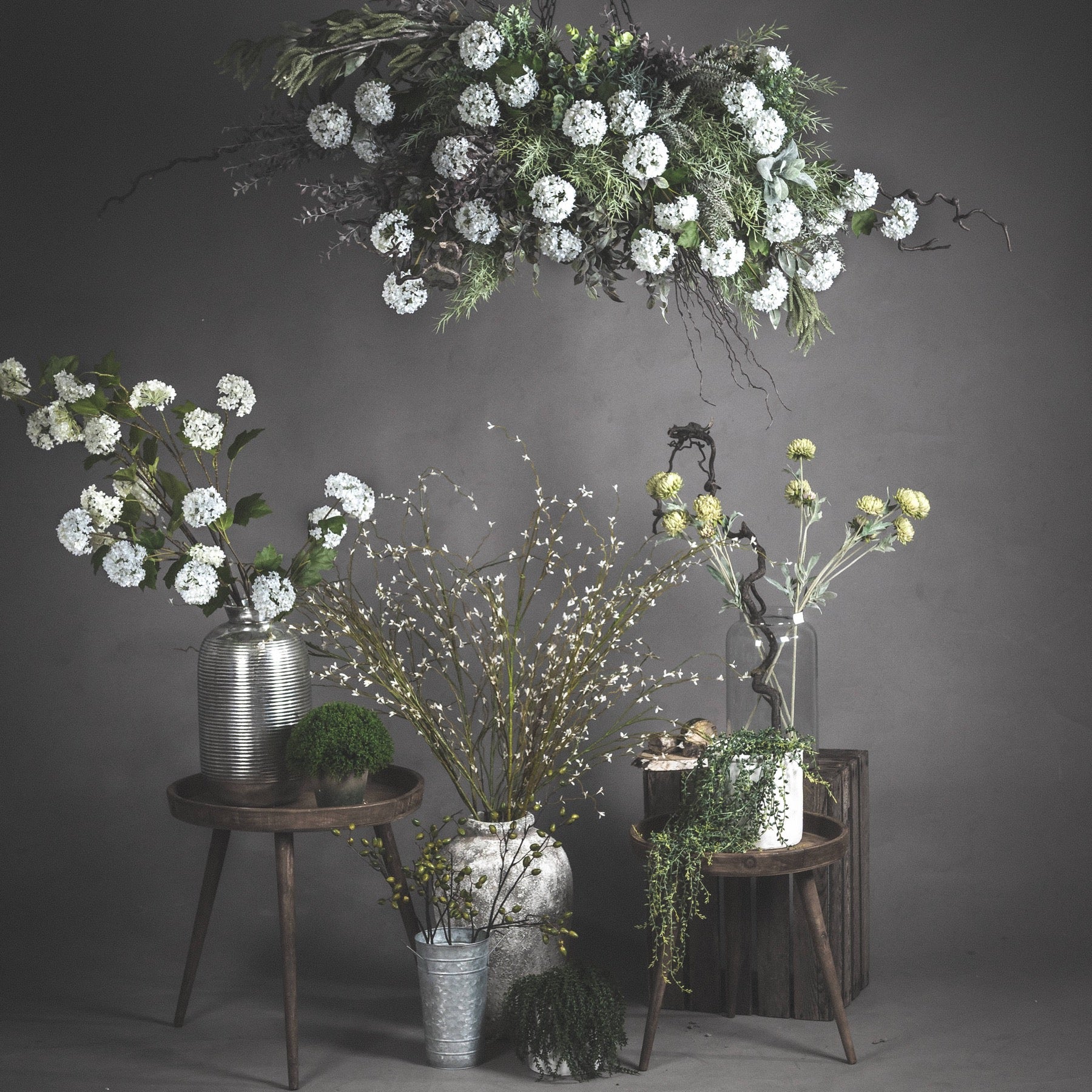 Tall white willow faux spray arranged in floor-standing ceramic vase with architectural composition