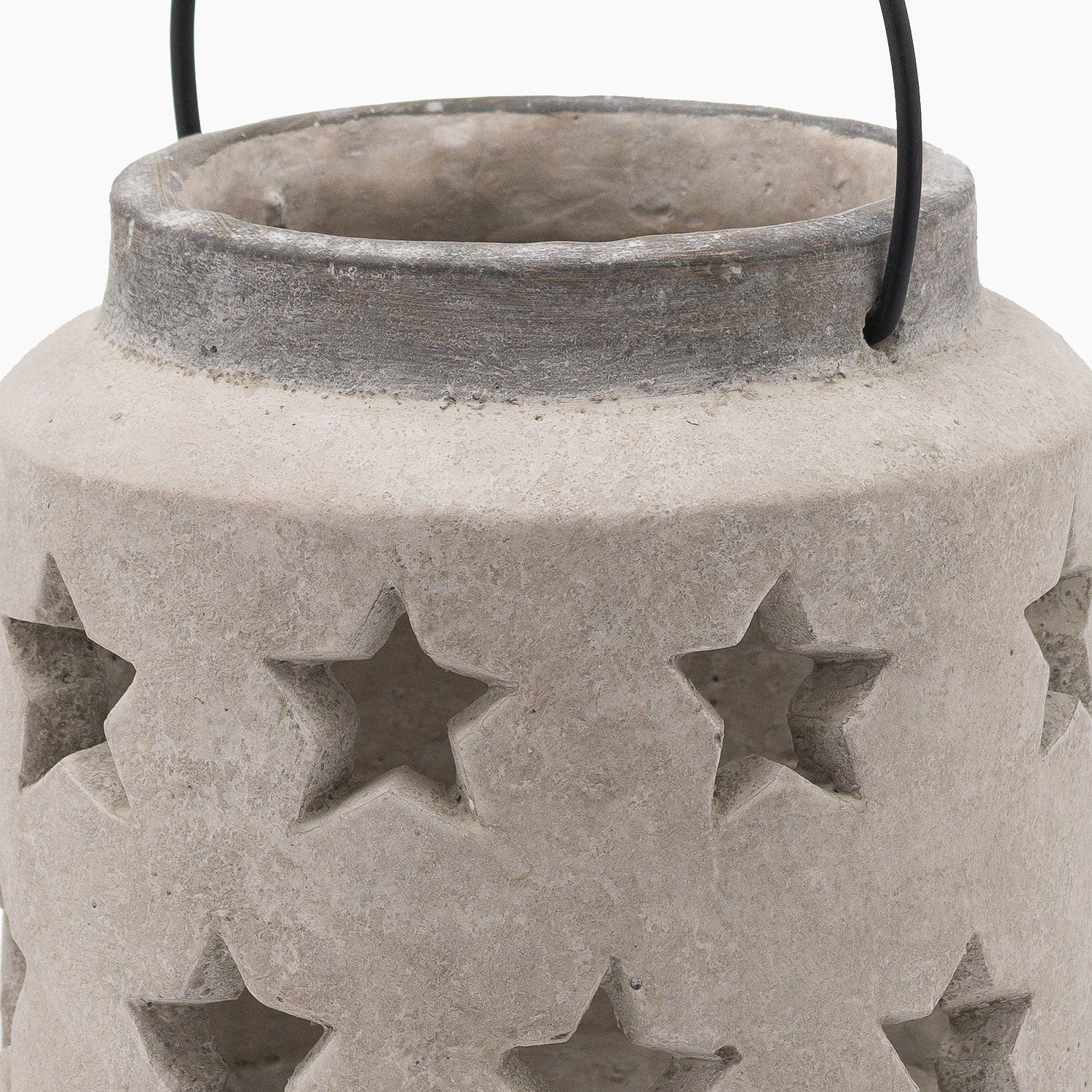 Side profile of solid stone lantern with star pattern and metal carry loop. Close-up of star-shaped perforations highlighting raw stone edges and texture