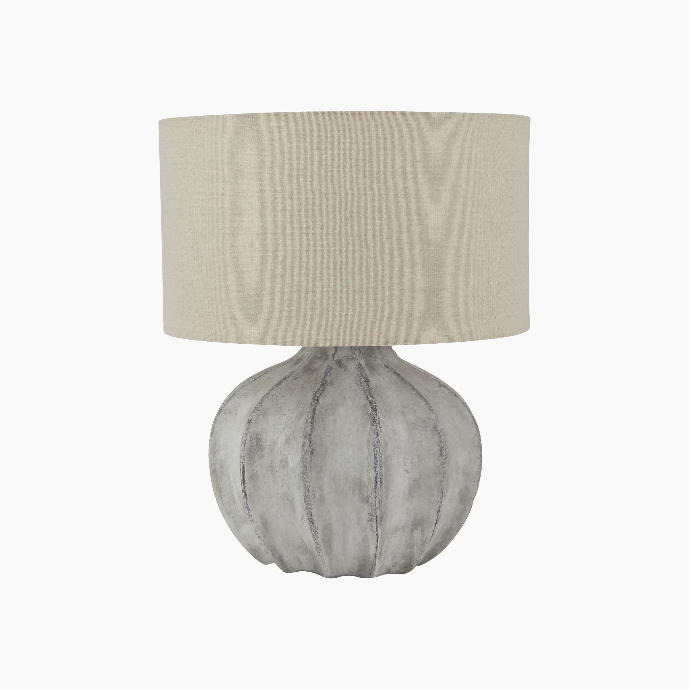 Front view of fluted stone ceramic table lamp with neutral linen shade