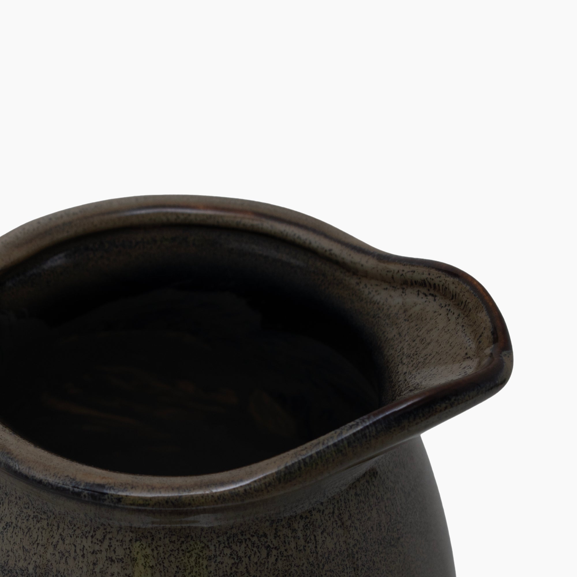 Side profile of the Gleaston Olive Jug Vase, showing the arched handle, tapered body, and organic surface detailing in crater-textured ceramic.
