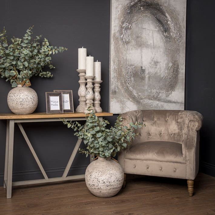 Lifestyle image of grey ceramic candle holder on wooden mantel with soft candle glow