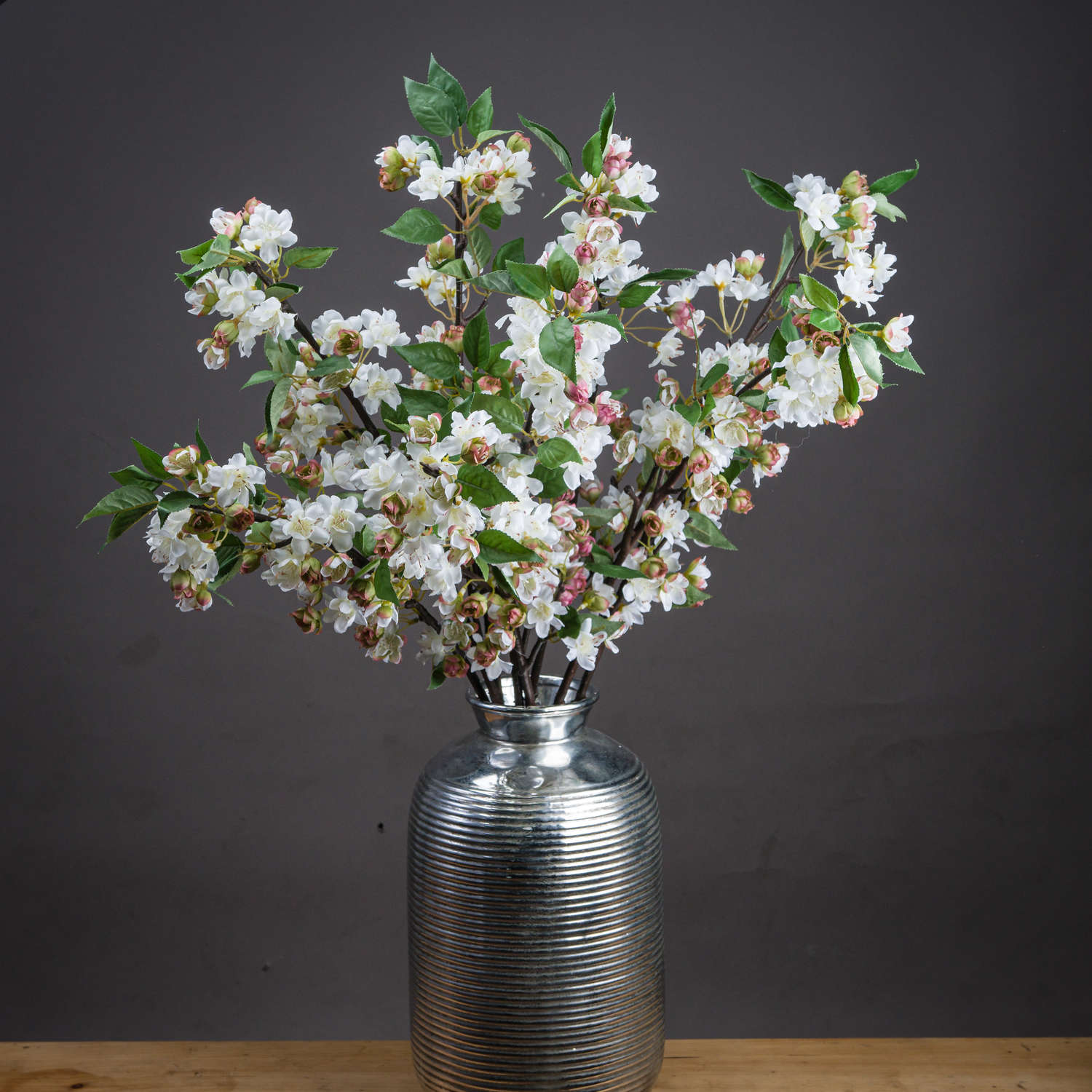 Pair of faux blossom stems arranged in a tapered vessel on light-toned surface