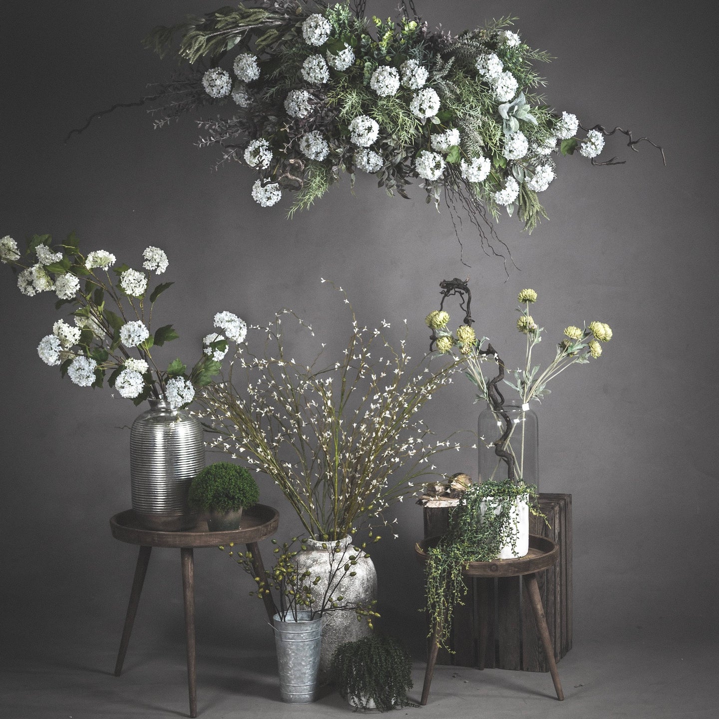 Group styling of White Willow Faux Spray with other faux florals in vases against a studio backdrop.